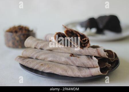 Fingerhirse-Crepes mit frisch geriebener Kokosnuss- und Palmsackfüllung. Aufgenommen auf weißem Hintergrund. Stockfoto