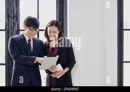 Ein Geschäftsmann und eine Geschäftsfrau, die in der Nähe eines Laptops stehen Fenster im Büro Stockfoto
