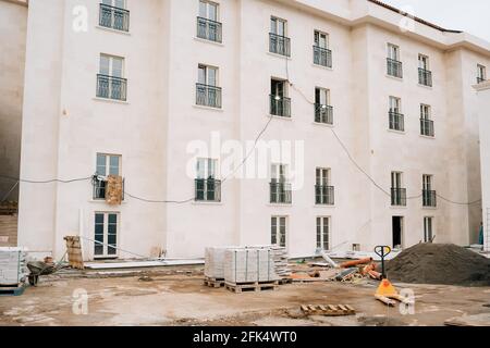 Fassade eines im Bau befindlichen Hauses. Baustoffe liegen auf Paletten Stockfoto