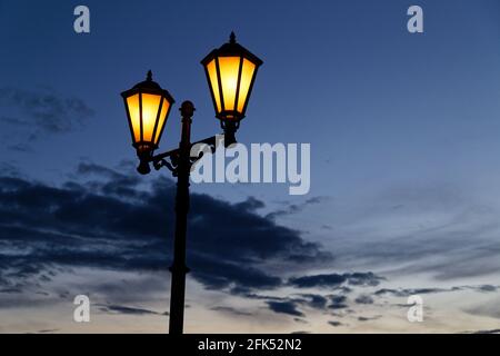 Vintage Laterne mit warmen gelben Licht und dunkelblau Nacht wolkigen Himmel auf Hintergrund Stockfoto