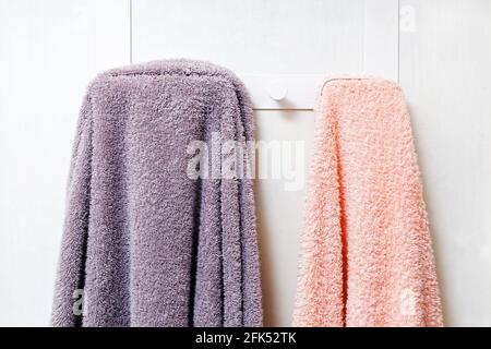 Nahaufnahme von zwei Frottee-Handtüchern, die auf dem weißen Tuch hängen Wand Stockfoto
