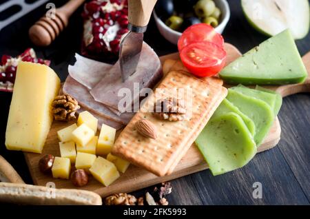 Verschiedene hausgemachte Stücke Käse mit Honig, Obst, Kekse und Nüsse auf dem Tisch. Frische Milchprodukte, gesunde Bio-Lebensmittel. Köstliche Vorspeise. Stockfoto