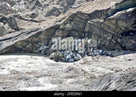 Der Schnack eines Gletschers, der Morraine trägt, wobei große Eisblöcke abgebrochen wurden und ein Schmelzwasserfluss ausströmt Stockfoto