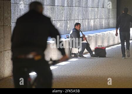 München, Deutschland. April 2021. Straßenmusiker in Zeiten der Coronavirus-Pandemie: Ein Musiker spielt am 28. April 2021 in einer Unterführung in München für Passanten die Klarinette. Credit: dpa/Alamy Live News Stockfoto