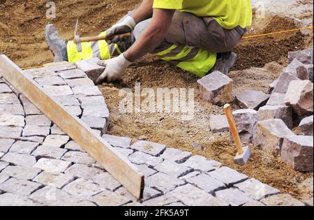 Die Arbeiter pflastern auf traditionelle Weise eine Straße. Stockfoto