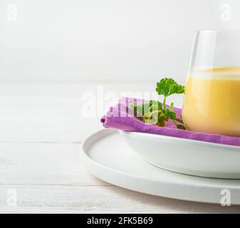 Hintergrund mit einem Teil eines Glases mit einem Milch-Mango-Getränk auf einem hellen Hintergrund. Stockfoto