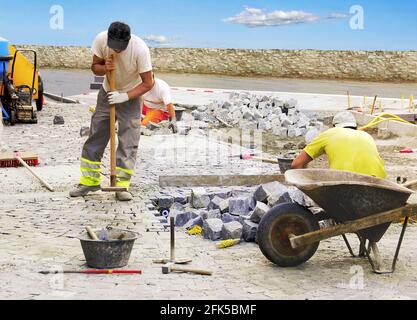 Die Arbeiter pflastern auf traditionelle Weise eine Straße. Stockfoto