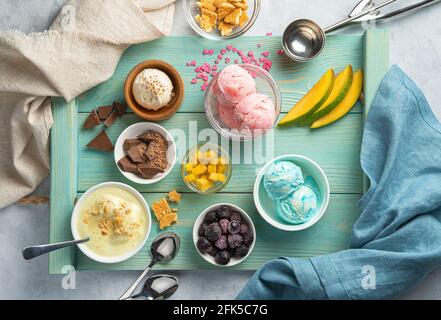 Speiseeis verschiedener Art, Früchte und gefrorene Beeren auf hellblauem Hintergrund. Stockfoto