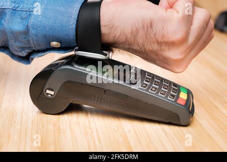 Kunden zahlen über die Smartwatch mit NFC-Technologie. Kontaktloser Zahlungsterminal. Stockfoto