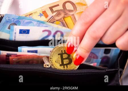 Virtuelle cryptocurrency Geld Bitcoin goldenen Münzen in der linken Hand einer Frau mit rotem Nagellack und den Geldbeutel. Die Zukunft des Geldes. Euro-banknoten. Stockfoto