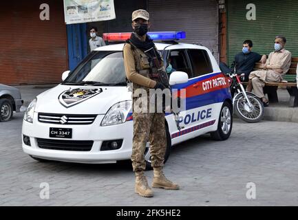 Peshawar. April 2021. Ein pakistanischer Soldat steht am 28. April 2021 auf einem Markt im nordwestlichen pakistanischen Peshawar Wache. Truppen der pakistanischen Armee wurden in 16 Städten des Landes eingesetzt, um die Einhaltung der COVID-19-Richtlinien durch die Öffentlichkeit zu gewährleisten. Quelle: Saeed Ahmad/Xinhua/Alamy Live News Stockfoto