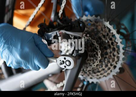 Vorarbeiter in Gummihandschuhen, die die Nahaufnahme des Fahrrads reparieren Stockfoto