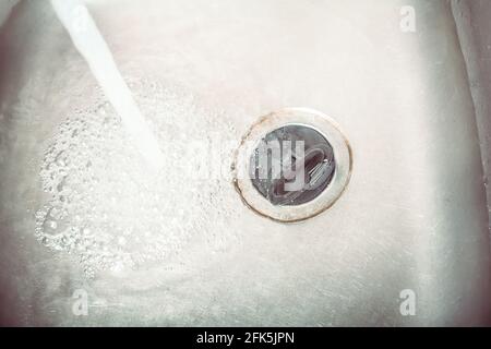 Wasserstrahl-Streaming in EINEM Waschbecken mit Ablassstopfen Stockfoto