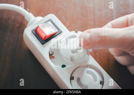 Führen Sie Die Sicherheitsstecker Des Babys Von Hand In Die Steckerleiste Ein – Kind Sicherheitskonzept Stockfoto