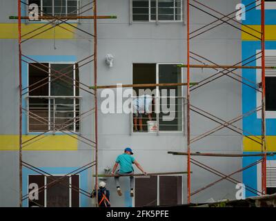 Guatapé, Antioquia, Kolumbien - April 4 2021: Männer bei der Arbeit malen ein Gebäude Grau mit Gelb Stockfoto