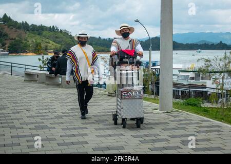 Guatapé, Antioquia, Kolumbien - 4 2021. April: Eine lateinische Frau und ein Mann sind in Ponchos und traditionellen Hüten gekleidet und verkaufen Kaffee auf der Straße Stockfoto