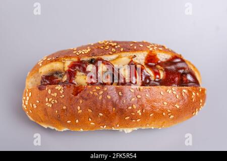 Hot Dog in einem knusprigen Brötchen mit Sesamsamen, Pilzen und Sauce. Stockfoto