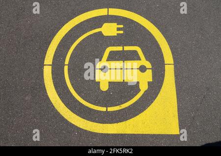 Gelbes Symbol für die Ladestation für Elektrofahrzeuge auf schwarzem Asphalt in der Stadt Zug, Schweiz Stockfoto