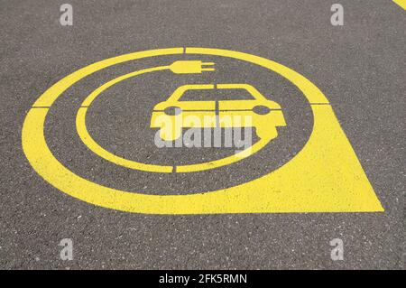 Niedrige Ansicht auf gelbem Symbol der Ladestation für Elektrofahrzeuge auf schwarzem Asphalt in der Stadt Zug, Schweiz Stockfoto