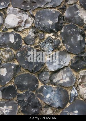 Nahaufnahme einer Steinwand aus Feuerstein an einer Suffolk-Kirche; ein traditionelles Baumaterial, in dem die Feuersteine geknickt oder geschnitten und nach Maß geformt werden. Stockfoto