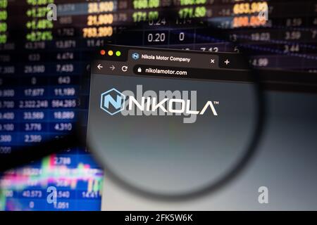 Nikola Firmenlogo auf einer Website mit verschwommenen Börsenentwicklungen im Hintergrund, die auf einem Computerbildschirm durch eine Lupe gesehen werden Stockfoto