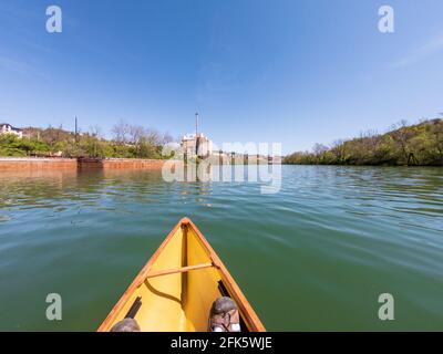 Kaukasischer Mann, der in einem Packkanu den Monongahela-Fluss in Morgantown, West Virginia, hinunter paddelt Stockfoto