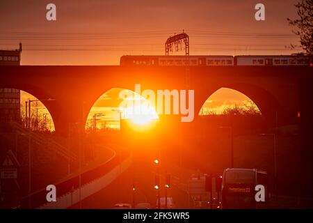 Sonnenaufgang im Stockport Viaduct, Greater Manchester. Ein Nahverkehrszug mit dem Northern Stockfoto