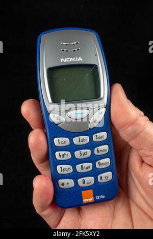 Ein Mann mit einem Orange Nokia 3210e-Telefon (das Nokia 3210e wurde ursprünglich 1999 veröffentlicht), Stockfoto