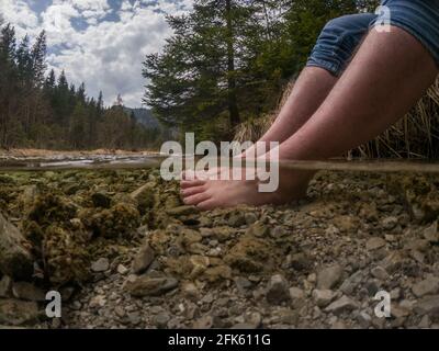 Wanderer kühlende Füße im kalten Bergfluss Stockfoto