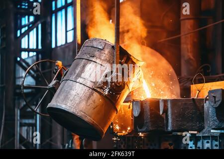 Metallgussverfahren in der Gießerei, flüssiges Metallgießen von Behälter zu Form mit Dampf- und Funkenstöcken, Hintergrund der Schwermetallurgie-Industrie. Stockfoto