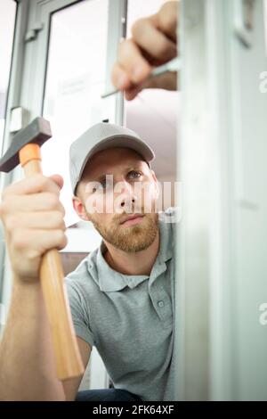 Gut aussehender Handwerker, der ein Türschloss reparierend einschloss Stockfoto