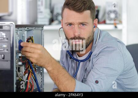Computeringenieur, der an einer defekten Konsole in seinem Büro arbeitet Stockfoto