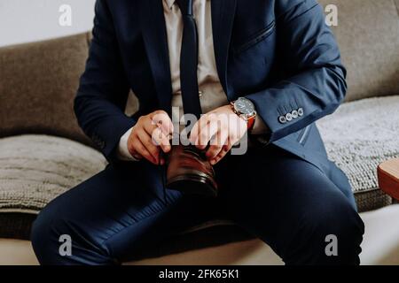 Nahaufnahme eines jungen Bräutigams, der seine Schuhe anzieht Stockfoto