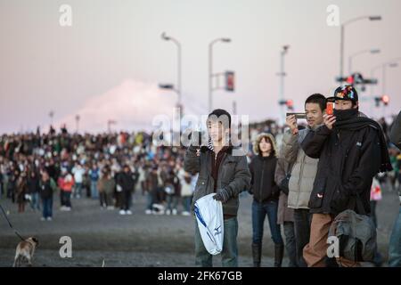 Japanische Männchen fotografieren am Kamakura-Strand, während die Sonne zu Beginn eines neuen Jahres auftaucht, mit dem Fuji-Berg im Hintergrund, Japan Stockfoto