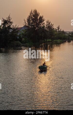 Fischer rudern sein Fischerboot am Fluss bei Sonnenuntergang, Hoi an, Vietnam Stockfoto