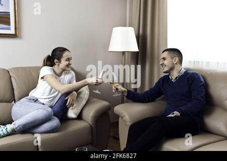 Wunderschöne kaukasisch lächelnde Paare, die ihre Weingläser beim Sitzen toasten Auf einem Ledersofa Stockfoto