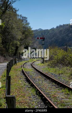 Bahngleise an einer Ecke neben einer unbefestigten Straße Mit einem Signal zur Seite Stockfoto