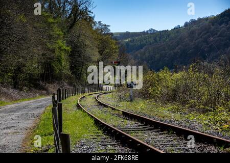 Bahngleise an einer Ecke neben einer unbefestigten Straße Mit einem Signal zur Seite Stockfoto