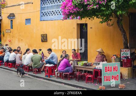 Überfülltes Straßencafe in der Altstadt unter wunderschönen Bougainvillea-Blumen, Hoi an, Vietnam Stockfoto