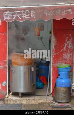 Kleiner Laden mit gedämpften Brötchen auf den Straßen von Shanghai. Mit traditionellen alten Bambusdampfern. Stockfoto