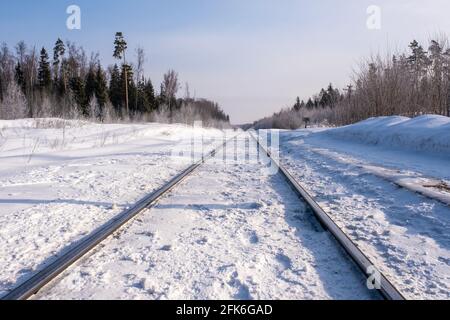 Glänzende Schienen einer Eisenbahn bedeckt mit weißem Schnee an einem sonnigen Wintertag, Russland. Stockfoto