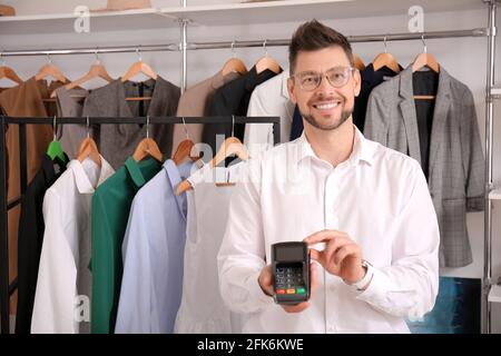 Verkäufer mit Zahlungsterminal im modernen Shop Stockfoto