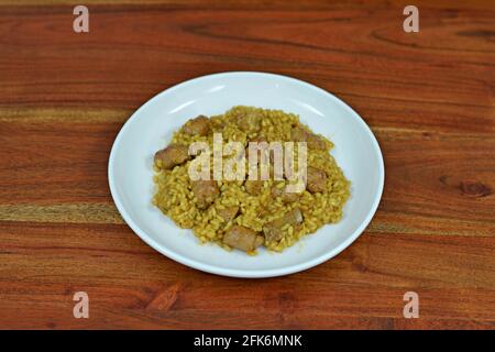 Teller mit spanischer Paella mit Fleisch auf einem Holztisch Stockfoto