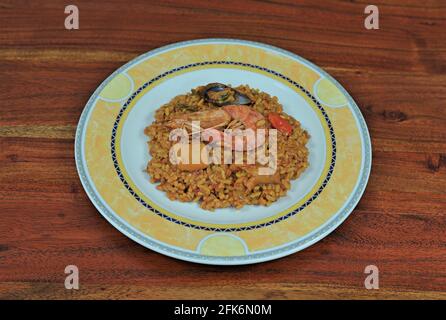 Teller mit spanischer Paella mit Meeresfrüchten auf einem Holztisch Stockfoto