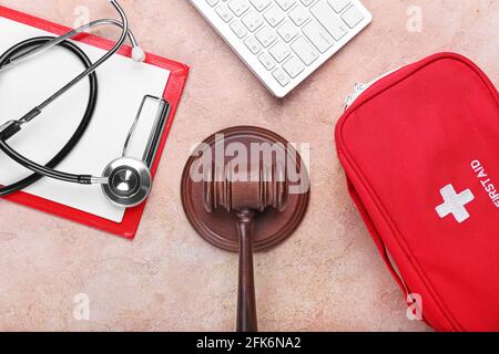 Richtergavel, PC-Tastatur, Stethoskop, Klemmbrett und erste-Hilfe-Set auf farbigem Hintergrund. Konzept der Gesundheitsreform Stockfoto