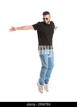 Springender junger Mann in Sonnenbrille auf weißem Hintergrund Stockfoto