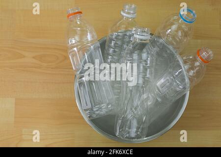 Entleerte recycelbare Flaschen aus klarem Kunststoff mit Mineralwasser in einem Schüssel auf Holzhintergrund mit Copyspace Stockfoto
