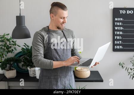 Junger Gärtner mit Laptop zu Hause Stockfoto