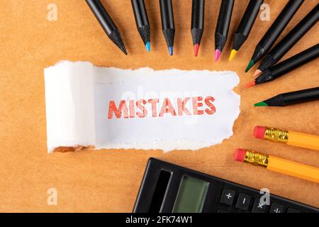 Fehler. Text unter zerrissenem Papier. Buntstifte auf orangefarbenem Hintergrund. Stockfoto