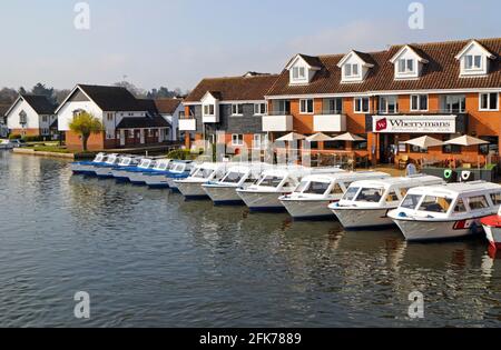 Blick auf eine Reihe von Day Hire-Booten auf dem River Bure auf den Norfolk Broads von der Brücke in Wroxham, Norfolk, England, Großbritannien. Stockfoto